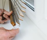 A male installing wooden blinds